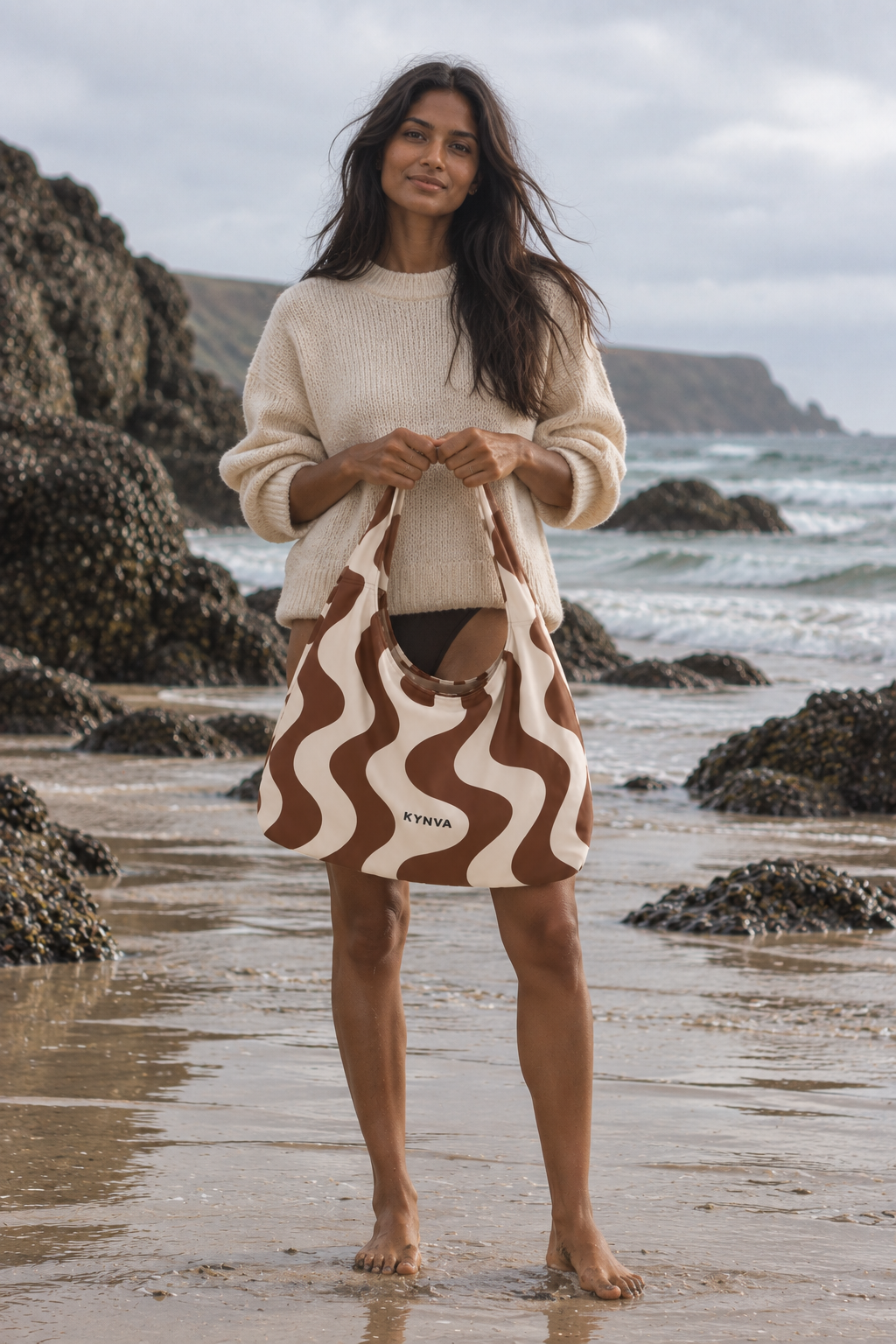 KYNVA Brown and Cream Wander waterproof hobo bag held on a Cornish beach