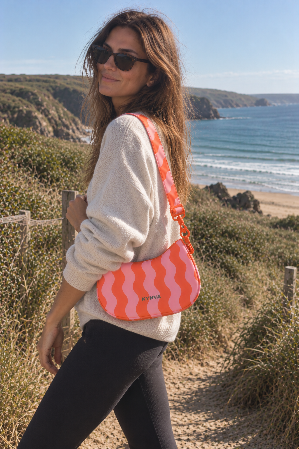 KYNVA pink and orange wave waterproof crossbody bag worn on a coastal walk in Cornwall